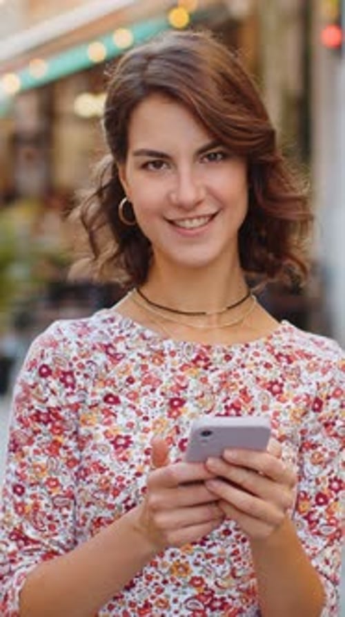 Smiling woman using a smartphone on city street