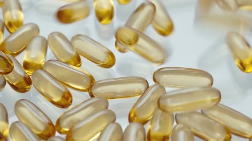 Shiny Omega 3 Capsules Falling onto a White Surface