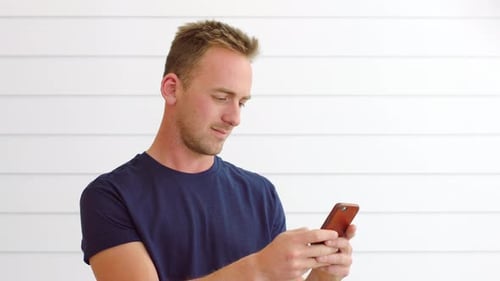 Man Uses Smartphone Against White Wall