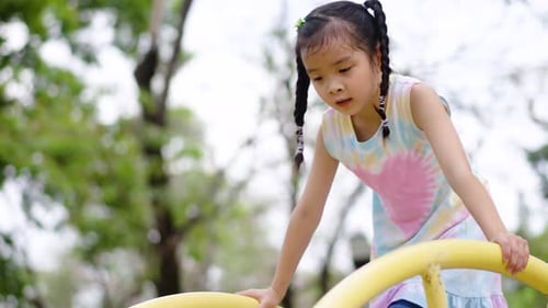 Adorable asian girl play on the playground in the park, hanging on their hands like monkeys