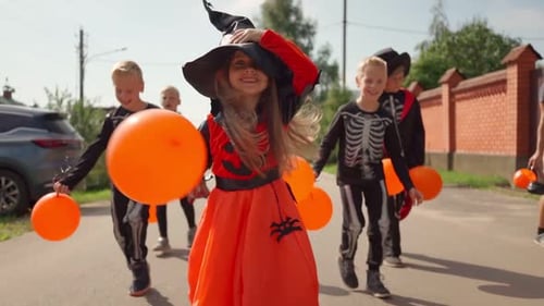 Kids in Halloween Costumes Running with Balloons