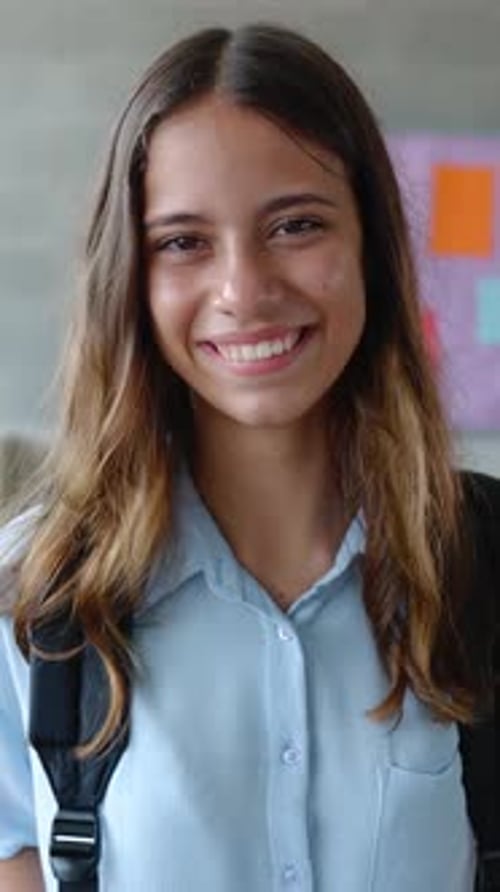 Smiling Primary School Student Girl with Backpack Standing at Classroom