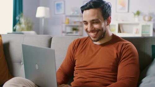 Smiling man using laptop on couch at home