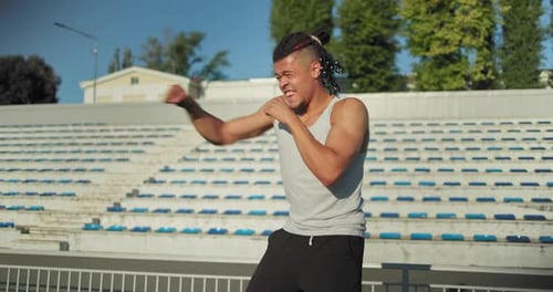 Junger afroamerikanischer Boxer, der in Zeitlupe boxt, trainiert im Stadion im Freien