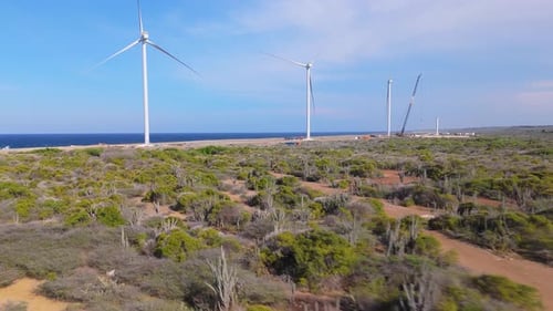 Aerial shot of windmills along the rocky coastline of an island, showcasing renewable energy and nat