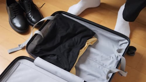 Packing Clothes into Suitcase for Travel Preparation