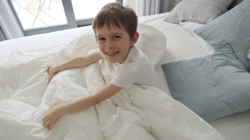 Happy Boy Smiling in Bed Indoors