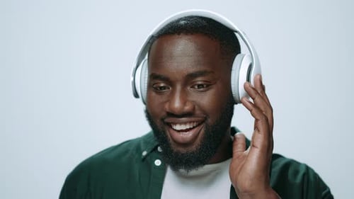 Bearded man with headphones listens and smiles