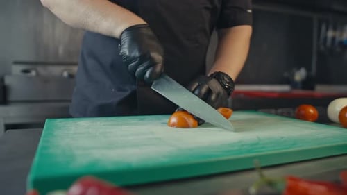 Chef Cutting Tomatoes in Professional Kitchen