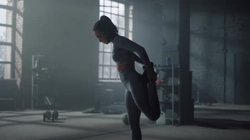 Athletic sportswoman stretching legs before intensity training in fitness gym