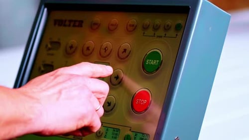 Bediener verwendet industrielles Bedienfeld mit Start- und Stopptasten