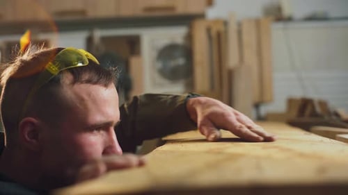 Craftsman Inspecting Wood in Workshop