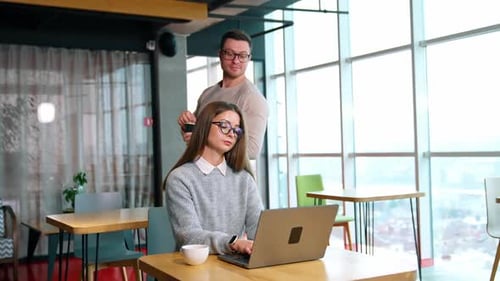 Langhaarige Frau, die im Büro an ihrem Laptop arbeitet.