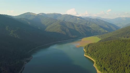 Aerial View of Big Lake with Clear Blue Water Between High Mountain Hills Covered with Dense