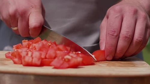 Person Dicing a Tomato on Cutting Board