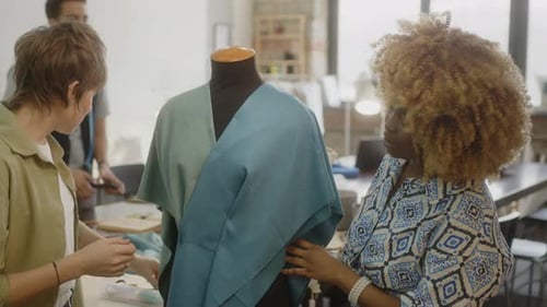Two Seamstresses Draping Fabric on Mannequin and Speaking