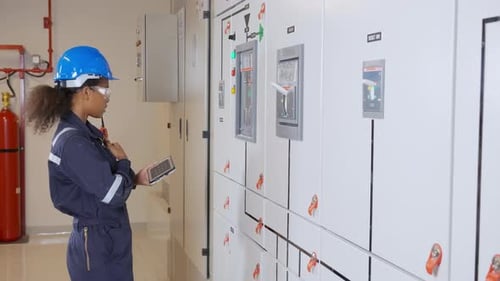 Engineer Inspecting a Control Panel with a Tablet