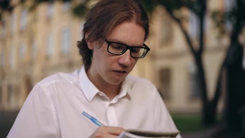 Young Adult Writing in Notebook Outdoors