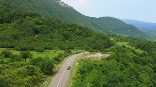 Cinematic drone captures shot of beautiful empty road. Camera flies behind car