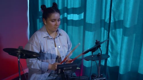 Woman at a drum kit in the room with neon lighting