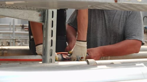 Arbeiter verbinden das Kabel im Werk mit Klebeband mit dem Rohr