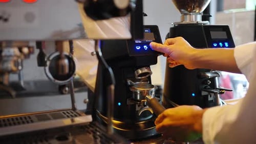 4K Barista grinding roasted coffee beans on grinder machine on counter at cafe.