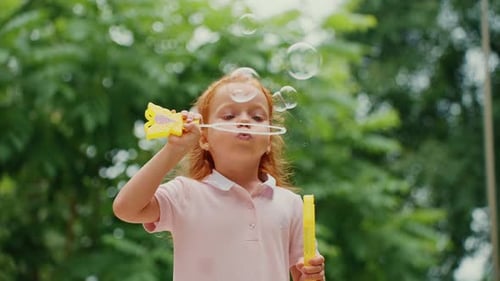 Little Girl Blowing Bubbles in the Park on a Sunny Afternoon