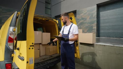 Delivery Man Checking Packages and Writing on Clipboard