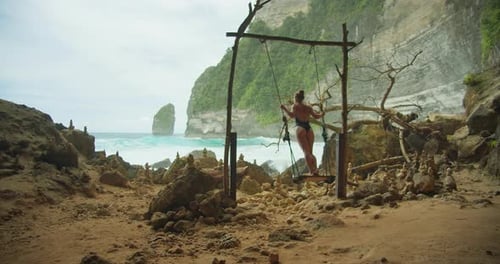 Serene Seascape with a Solitary Swing A Peaceful Retreat By the Sea Woman Swinging on Beach