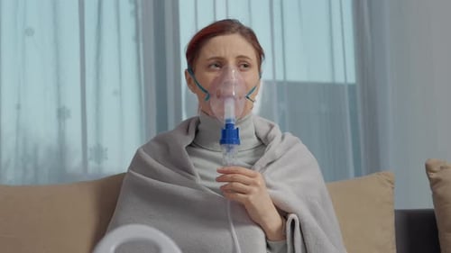 Une femme utilise un nébuliseur pour inhaler une solution saline pour le traitement de la toux à la maison