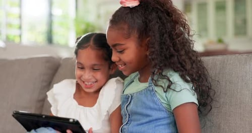Two Girls Using Tablet Together on Sofa