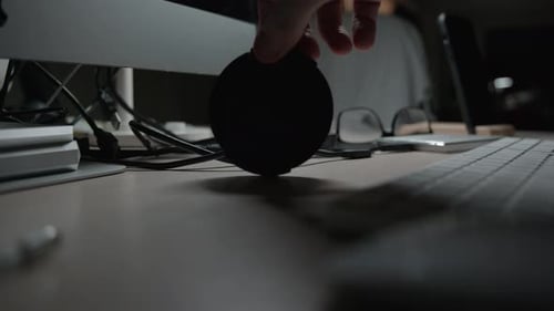 Hand Places Headphones on Desk With Computer