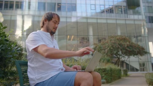 Junger Geschäftsmann schaut müde auf einen Laptop, schließt ihn und genießt Ruhe nach einem Arbeitstag