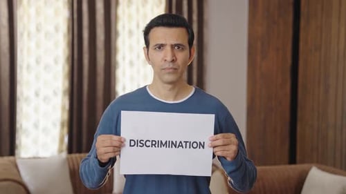 Adult Holding a Discrimination Sign in Home