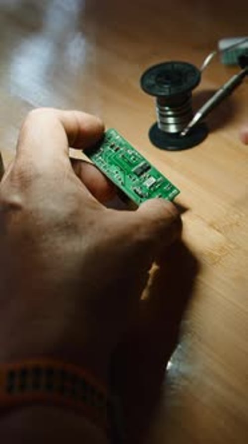 Electronic Technician Soldering Components Onto a Circuit Board in a Workshop