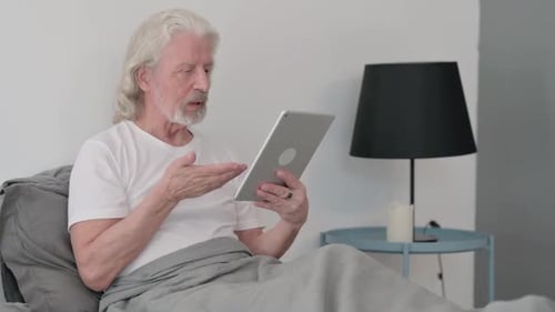 Senior Man Video Chatting While Lying in Bed