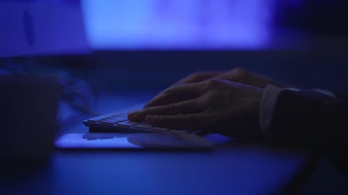Une personne tape tranquillement sur un clavier dans un environnement de travail moderne et sombre