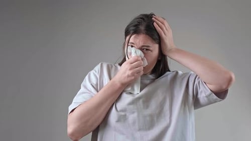 Woman Holding Tissue to Nose in Studio