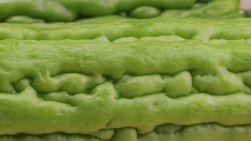 Une gourde amère, un légume souvent utilisé comme ingrédient en cuisine, est posée sur une table en bois.