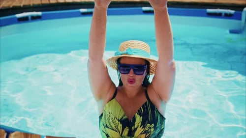 Woman in Colorful Swimsuit Enjoying a Sunny Day in a Swimming Pool with Vibrant Water Reflections