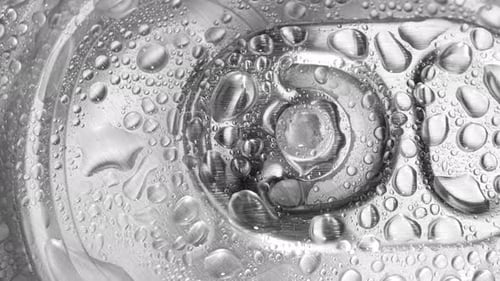 A close-up view of the top of a beverage can with water droplets.