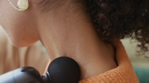 Woman Using Percussion Massage Gun on Neck at Home