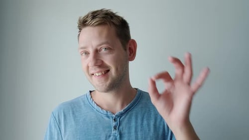 Man Giving OK Hand Gesture in Front of Wall