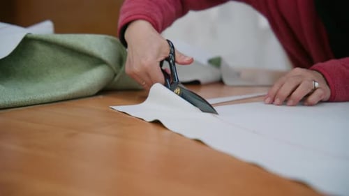 Woman Cutting Fabric on a Table with Scissors