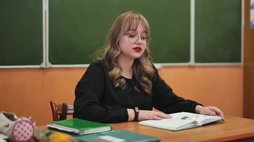 Young Woman Reads from Textbook in Classroom