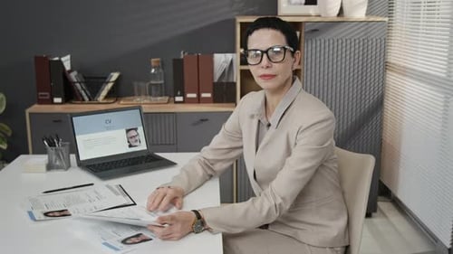 Portrait of Elegant Mature Female HR Specialist at White Desk during Workday