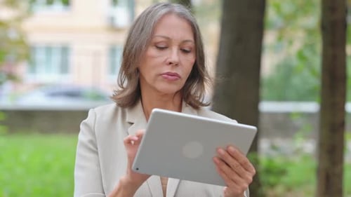Portrait of Old Woman Using Tablet Outdoor