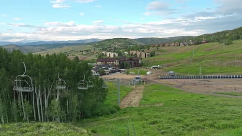 Aerial flyover above cable lines of ski lift to resort in summer