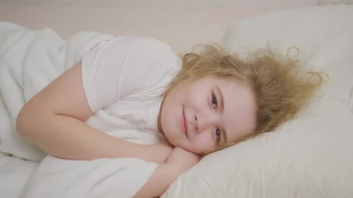 Smiling Girl Lying on Pillow in Bed