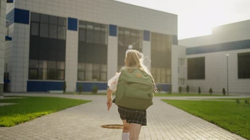 Kind, Mädchen, das zum Gebäude einer modernen Schule rennt, Rückansicht, positive Gefühle, Zurück zur Schule
